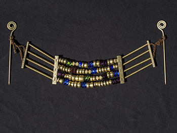 Krūtinės papuošalas iš žalvario ir stiklo karolių bei skirstiklių. X –XIa. Kuršiai.